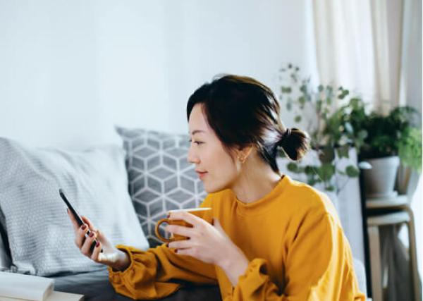 Woman at home looking at her phone with coffee