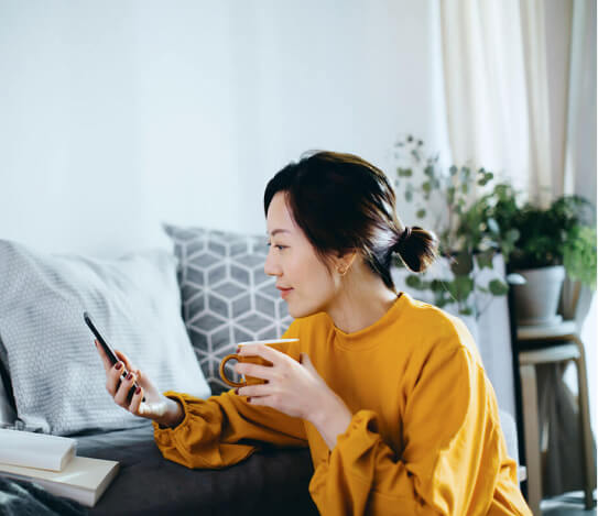 Woman at home looking at her phone with coffee