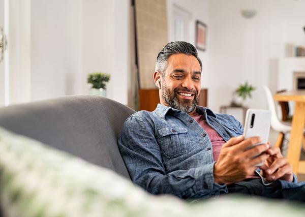 Man on couch smiling with cell phone