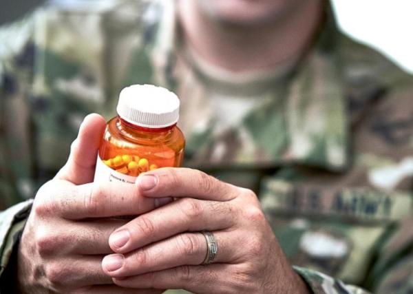 man in uniform examining pill bottle