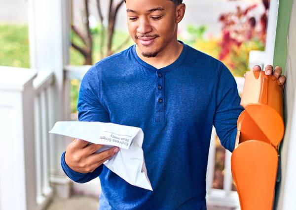 Man reviewing prescription documnt on front porch of home.