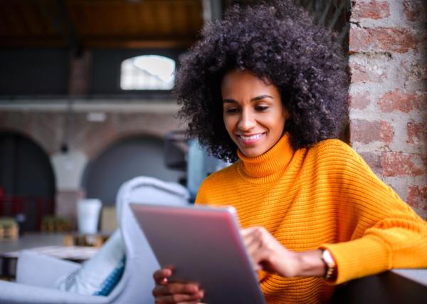 Woman in an orange sweater holding a tablet