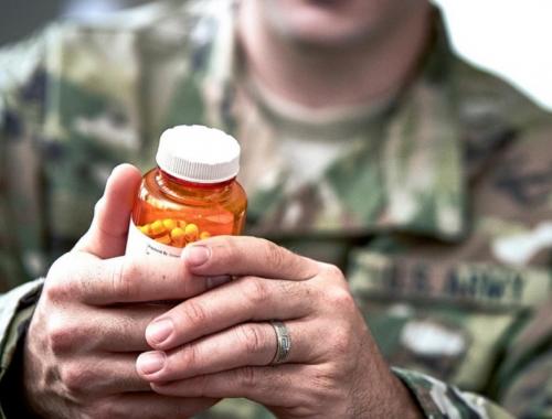 man in uniform examining pill bottle