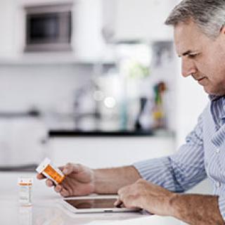 Older man holding medication bottle.