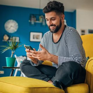 man on arm chair holding mobile phone