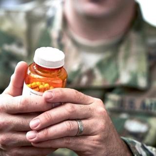 man in uniform examining pill bottle