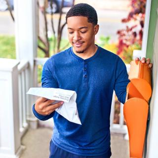 Man reviewing prescription documnt on front porch of home.